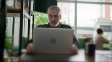 Erkek girişimci sehpada dizüstü bilgisayar açıyor. Kafede çalışan orta yaşlı bir insan modern teknoloji bilgisayarı kullanıyor.
