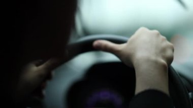 Driver holding steering wheel stopped in traffic waiting, close-up woman hands