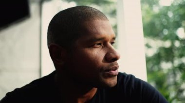 Meditasyon yapan genç bir adam hayatı derin derin düşünüyor. Düşünceli bir Afrikalı Amerikalının yakın plan portresi.