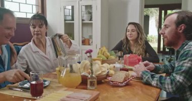 Aile kahvaltıda konuşuyor. Yetişkin kız ve erkek çocukları ile konuşan orta yaşlı evli bir çift. İnsanlar kahvelerini yudumluyor, sohbet ediyorlar.