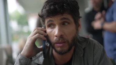 30 'lu yaşlarda bir adam telefonda konuşuyor. Elinde akıllı telefon cihazıyla gülümseyen biri konuşuyor. İletişim için modern teknoloji aygıtı