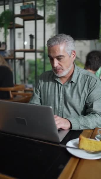 老企业家坐在咖啡店 笔记本电脑盯着屏幕 在垂直视频咖啡店用电脑遥控操作的女上司 — 图库视频影像