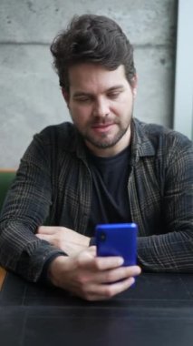 Genç adam cep telefonu cihazına bakıyor. Milenyum insanı elinde akıllı telefon ile çevrimiçi internete bağlanarak dikey videoda geziniyor..