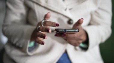 Closeup of a black woman hands holding cellphone device scrolling screen. African American person holding phone touching screen