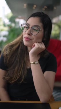 Kafede oturan pencereye bakan düşünceli genç bir kadın. Kafe restoranında saçlarıyla oynayan 20 'li yaşlardaki dalgın kız..