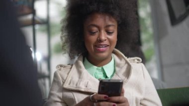 Genç bir siyahi kadının elinde akıllı telefon cihazıyla mesaj gönderme fikri var. Cep telefonu kullanan Afrikalı Amerikalı bir kız..