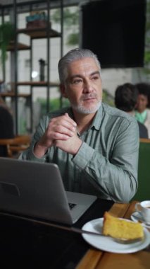 Düşünceli, yaşlı bir işadamı kafeteryada oturmuş tefekkür ediyordu. Dikey Videoda pencereden dışarı bakan düşünceli üst düzey yönetici