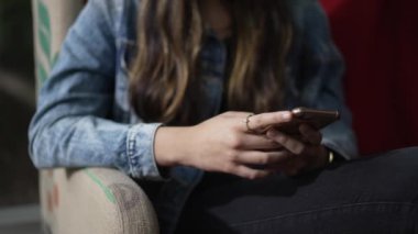 Kanepede oturan telefonu kullanan genç bir kadın. Akıllı telefonla mesaj yazan kişiyi kapat