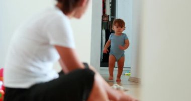 Baby development walking at home indoors. One year old toddler infant learning to walk