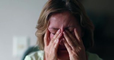 Worried older woman portrait feeling anxiety. Senior woman in 60s covering face