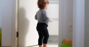 Baby standing by home bathroom, one year toddler stands observing