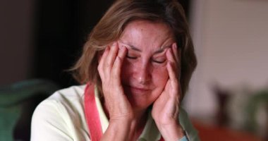 Older woman feeling stress and pain, anxious person covering face with hands feeling anxiety