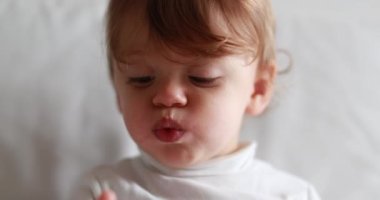 Cute one year old baby with mouth full snacking. Portrait of child eating and chewing