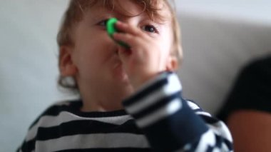 Baby trying to inflate balloon, portrait of one year toddler boy blowing air inside balloon