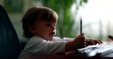 Baby at home office pretending to work in front of computer desk. One year old toddler child