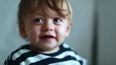 Cute baby boy turning head towards camera. Adorable sweet one year old child portrat smiling to camera