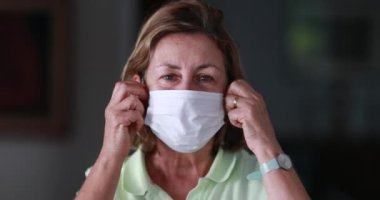 Portrait happy older woman removing surgical mask after ilness. Senior woman sickness recovery feeling relief