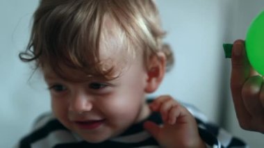 Teasing baby by deflating balloon to one year old child face