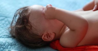 Baby rubbing eyes with hand. Tired one year old infant rubs eye, infant wanting to sleep