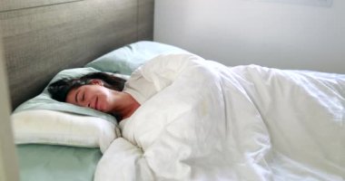 Funny woman lying in bed snoozing in the morning waking up