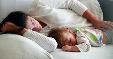 Mother sleeping with baby infant in couch together