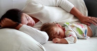 Mother and child asleep on couch napping together