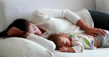 Mom and baby sleeping together in afternoon nap. Mother and infant asleep in couch