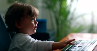 One year old baby child in front of computer desk. Toddler pretending to work at office