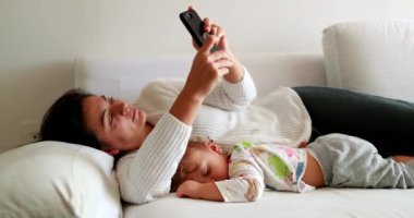 Tired mother rubbing face with hand while multi-tasking motherhood with work