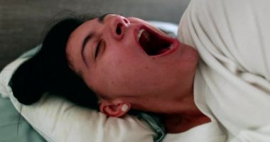 Woman stretching body yawning and waking up in morning bed