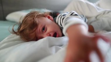 Upset baby infant having a tantum in morning bed. Angry toddler tearful child boy cries having tantrum
