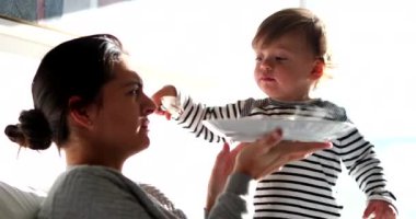 Baby boy feeding mother food, funny toddler child feeds parent