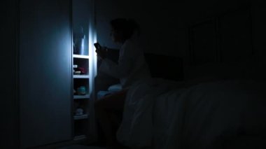 Woman flashing light looking inside closet in the middle of the night