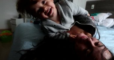 Baby and mother having fun together rolling on bed