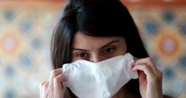 Woman putting on face mask, virus pandemic prevention surgical mask portrait during coronavirus