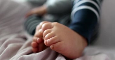 Toddler boy touchign toes. one year old Infant child baby feet