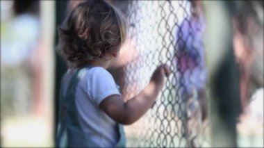 Child watching game leaning on fence, video 