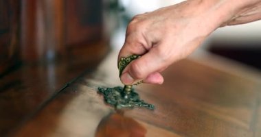 Close-up hand removing key from antique furniture