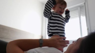 Mother and child in bed in the morning. Happy toddler boy jumping in bed