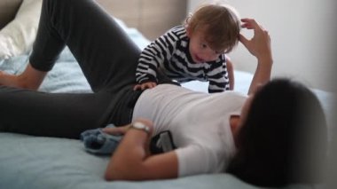 Mother and child in bed in the morning. Happy toddler boy jumping in bed