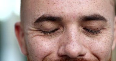 Derin düşüncelere dalmış genç adam gözlerini kapatıyor, derin bir nefes alıyor, rahatlamış hissediyor. yakın çekim gözler portre yüzü