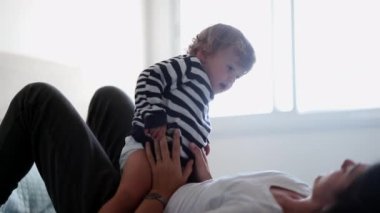 Mother and child in bed in the morning. Happy toddler boy jumping in bed