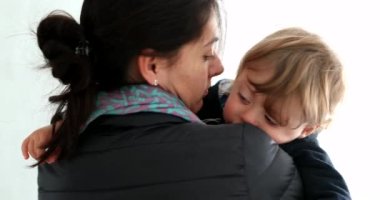 Mother holding crying baby toddler. Mom caring calming down tearful child son