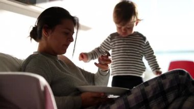 Mother and baby infant together in morning eating breakfast casually. Mom and toddler casual scene