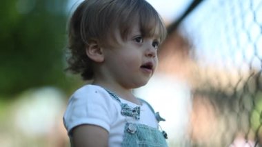 Child watching game leaning on fence, video 