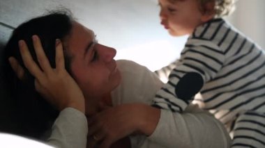 Mother and baby son in bed in the morning, candid family interaction relationship