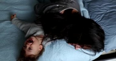 Happy baby and mother having fun together rolling on bed laughing and smiling