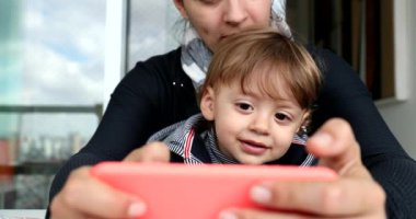 Parent and child using cellphone. Mother and toddler holding smartphone