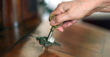 Close-up hand inserting key in antique furniture