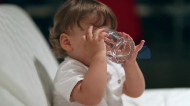 Cute baby boy drinking glass of water multiple times